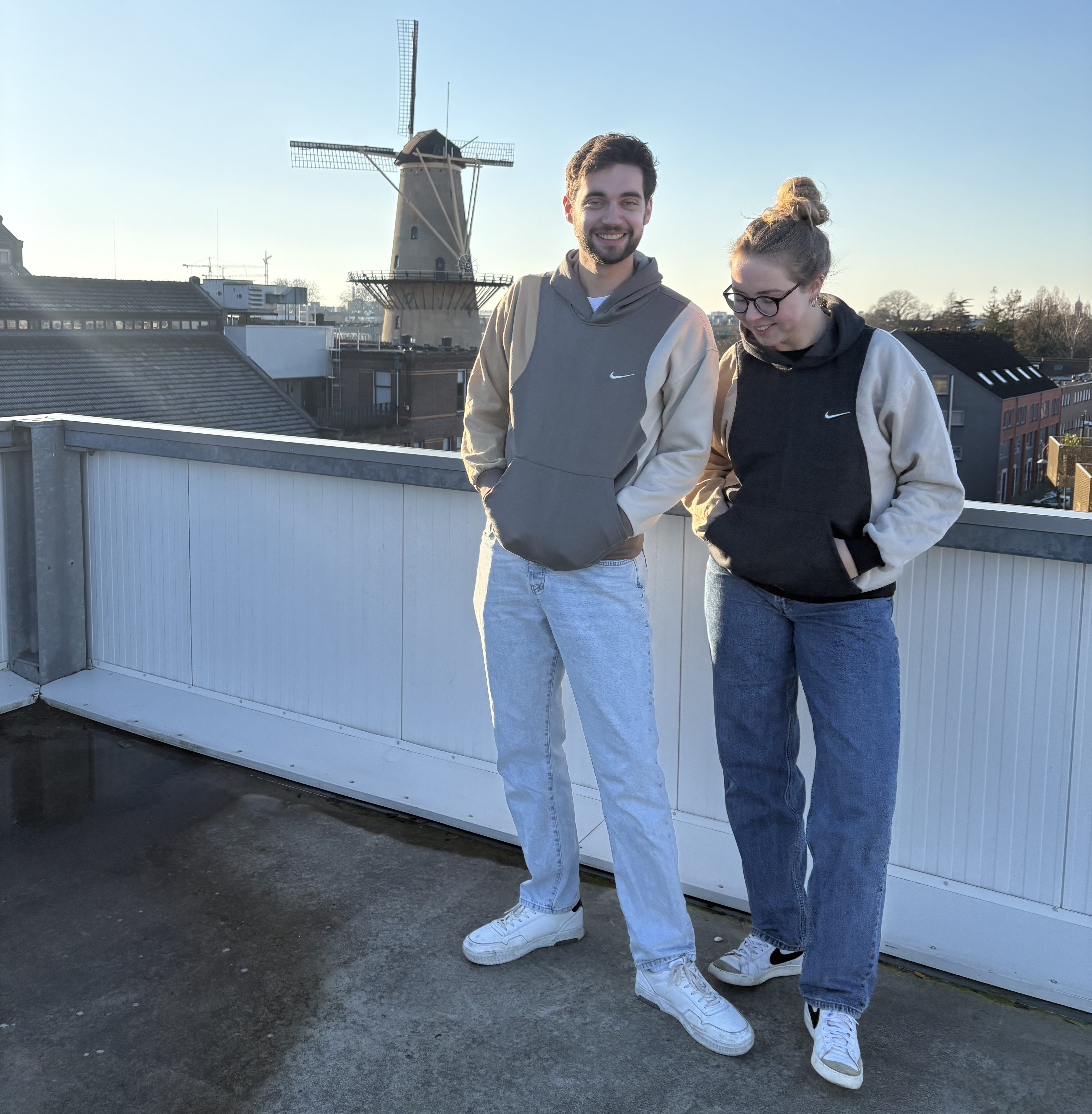 reworked sweaters (reworked sweatshirts) bij 2 mensen die geposeerd staan voor een Nederlandse molen. De truien zijn gerecycled en goed voor de planeet.